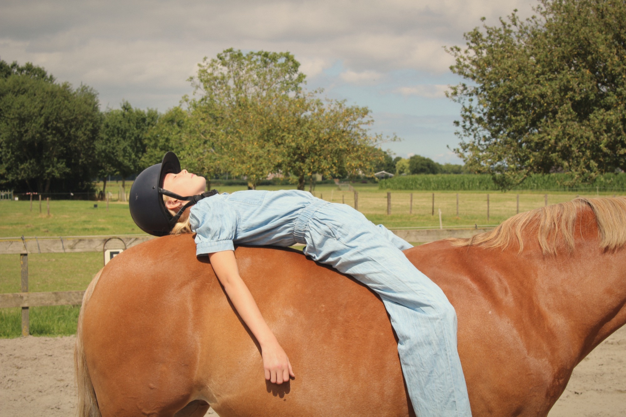 Een kind ligt ontspannen op de rug van een paard