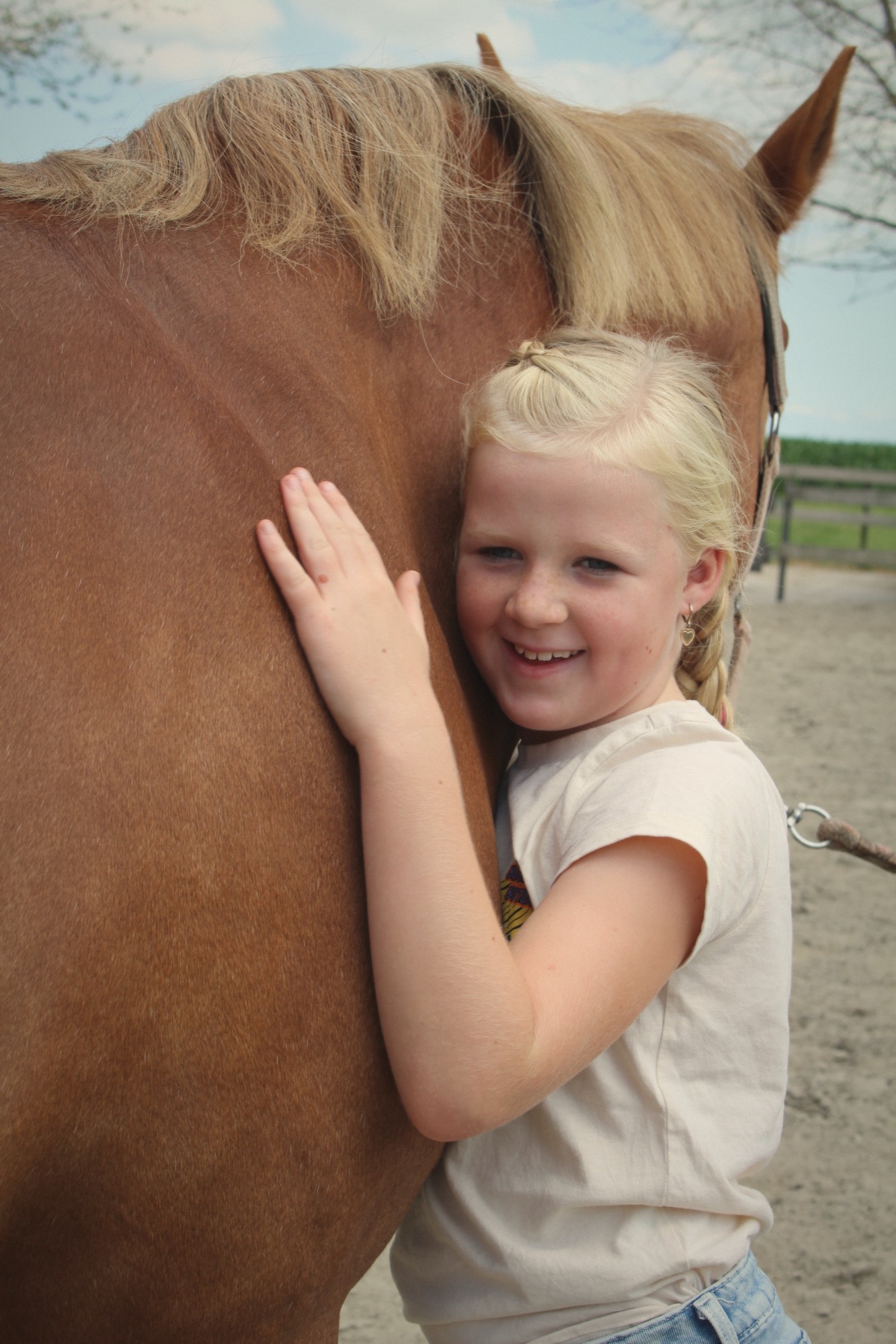 Een meisje leunt tegen een paard aan, met haar hand op zijn hals